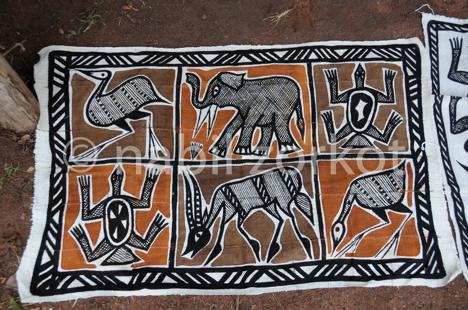 Africa photo — Un tapis artisanal représentant six animaux africains stylisés : une girafe, un éléphant, deux zèbres et deux antilopes, disposés en tr