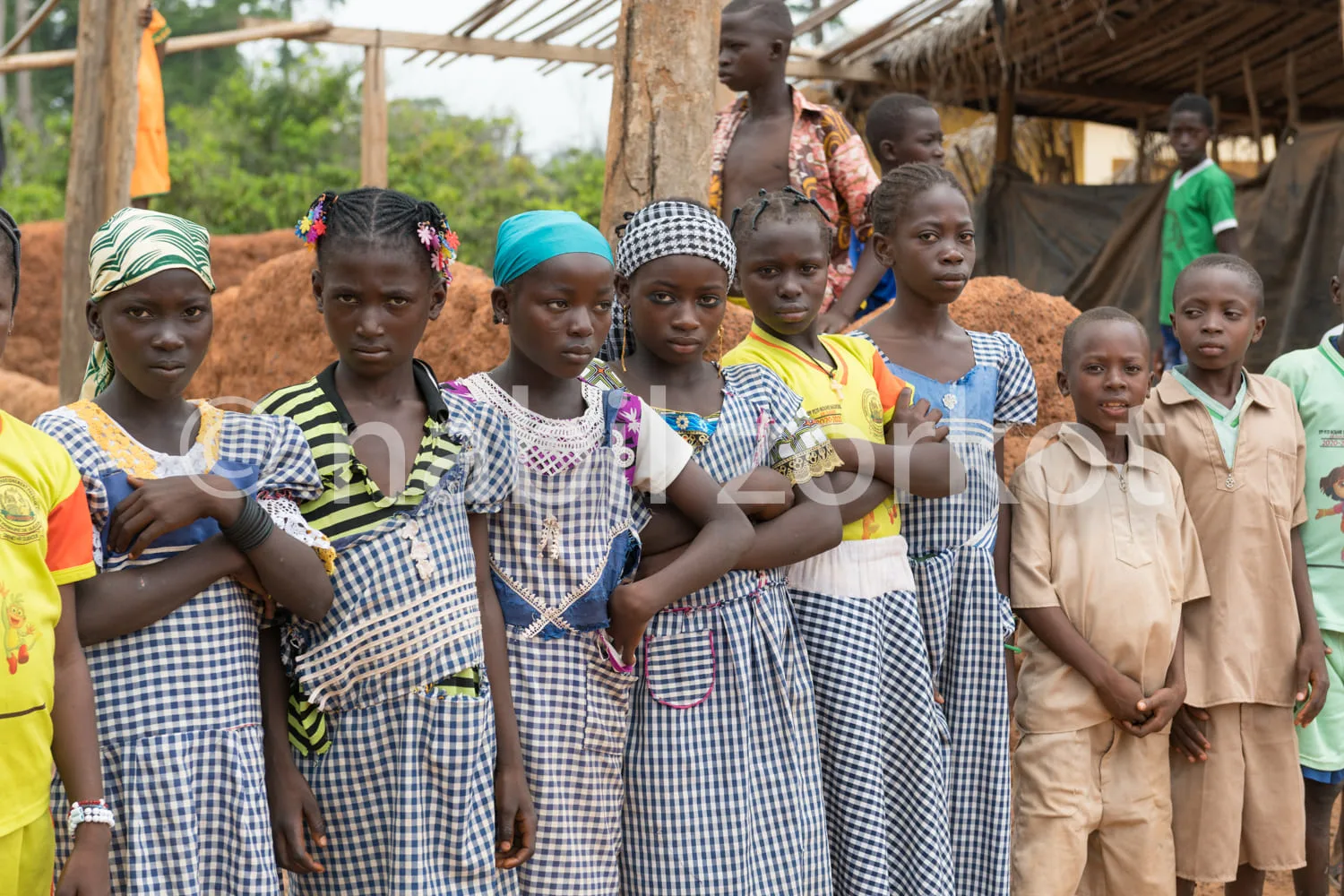 Africa photo — Un groupe de huit enfants, dont sept filles en robes d’uniforme bleu et blanc avec des coiffures variées et un garçon en tenue beige, p