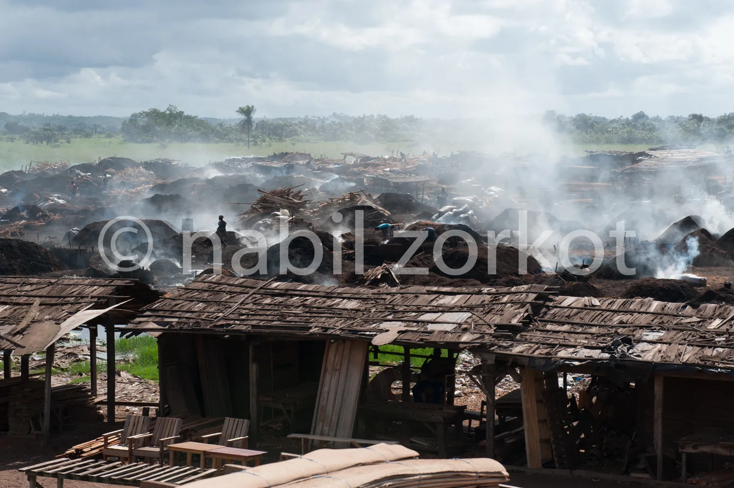 Africa photo — Vue aérienne d’un incendie important dans une déchetterie en milieu rural, avec des fumées épaisses s’élevant des tas de déchets et de